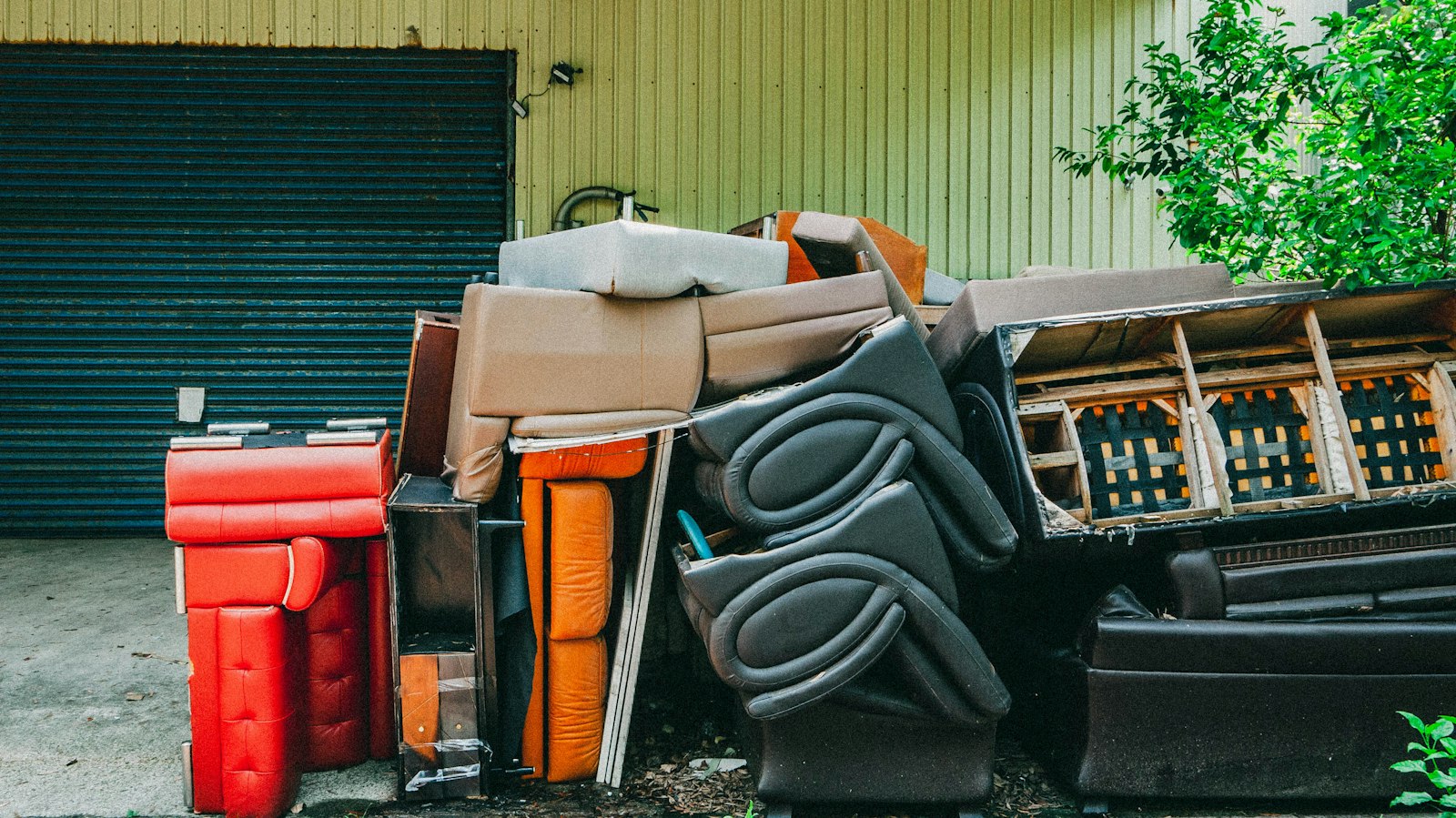 Muebles y colchones acopiados frente a un garage para su retiro